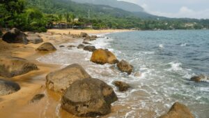 Uma praia serena com rochas e água cristalina, perfeita para uma escapada relaxante.