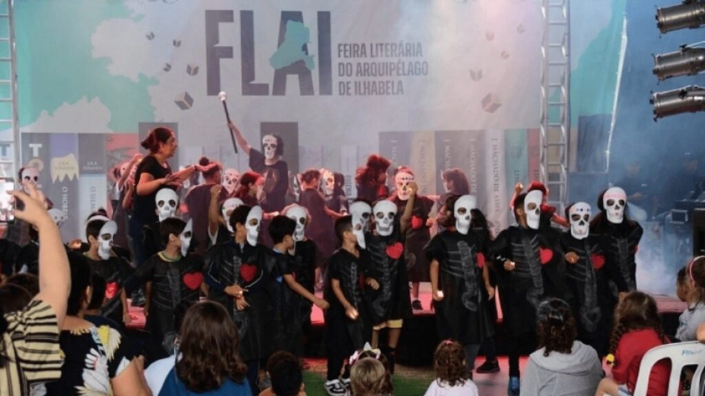 Crianças usando máscaras em palco durante uma peça teatral.