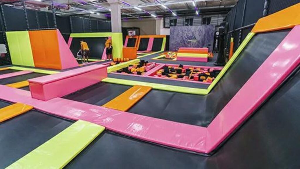 Um parque de trampolins coberto grande com tapetes coloridos.