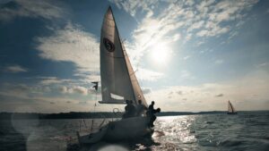 Um veleiro navegando na água com o sol brilhando intensamente acima.