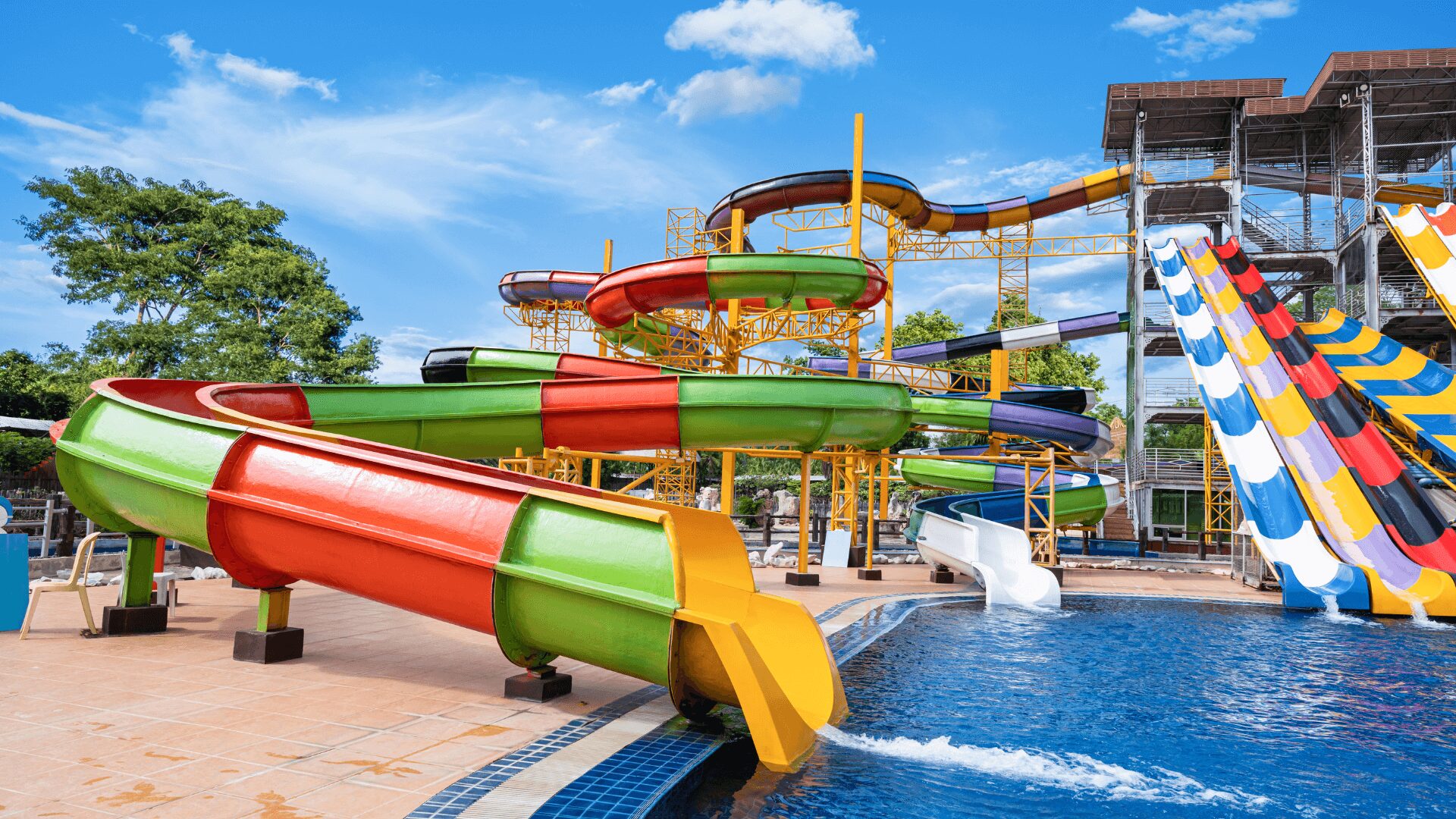 Toboáguas coloridos giram e giram sobre uma piscina azul, sob um céu claro, em um parque aquático animado.
