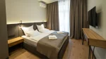 Quarto de hotel moderno e aconchegante com duas camas de solteiro juntas, móveis de madeira clara e iluminação suave embutida na cabeceira.