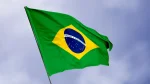 Bandeira do Brasil hasteada e balançando em um mastro em um céu nublado, simbolizando a celebração do feriado de 7 de setembro.