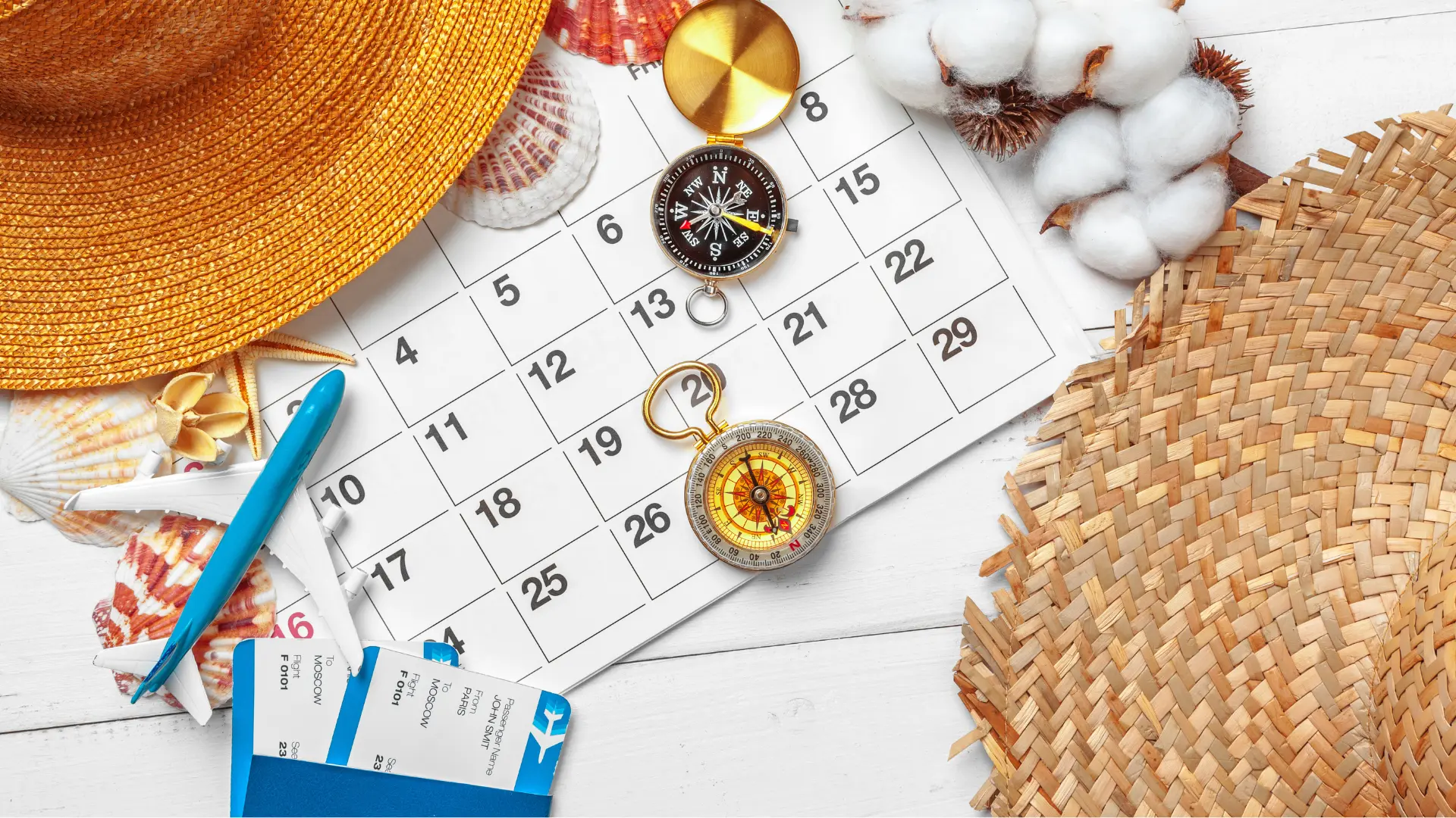 Uma mesa decorada com itens de viagem, como chapéus de sol, conchas, bússolas e passagens aéreas, dispostos ao redor de um calendário. A imagem ilustra o planejamento para aproveitar ao máximo os feriados e folgas do segundo semestre de 2026.
